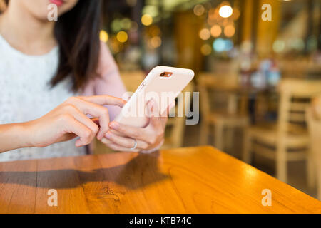Donna al lavoro su cellulare all'interno di coffee shop Foto Stock