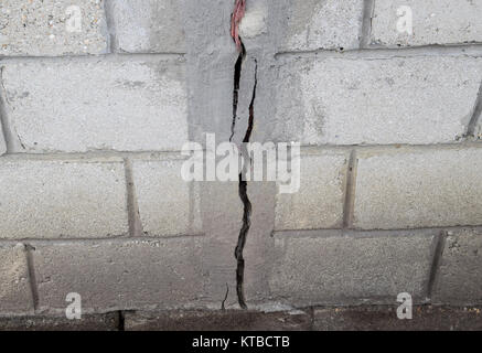 Una crepa nel muro di cemento. La distruzione del muro da blocchi grigi Foto Stock