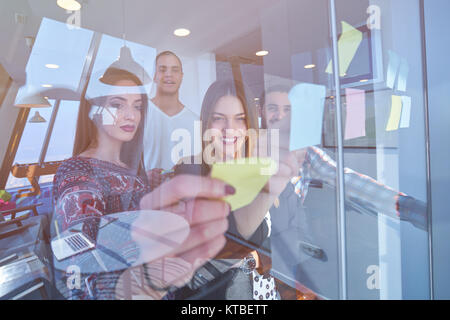 Business, avvio, pianificazione, gestione e persone concetto - happy team creative di scrittura su adesivi a office scheda di vetro in un ufficio moderno Foto Stock