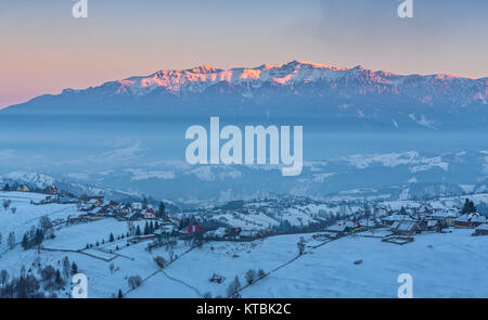 Magnifica vista rurale con la snowy Rucar-Bran passano nella valle delle montagne di Bucegi al tramonto, Pestera village, Brasov county, Transilvania regione Foto Stock