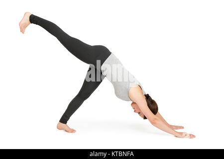 Ganzkörper-Ansicht einer jungen schwarzhaarigen Frau auf weißen Hintergrund in eine Variante der Yoga-Position herabschauender Hund (adho muka shavasana). Foto Stock