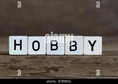 Hobby, scritto in cubi su uno sfondo di legno Foto Stock