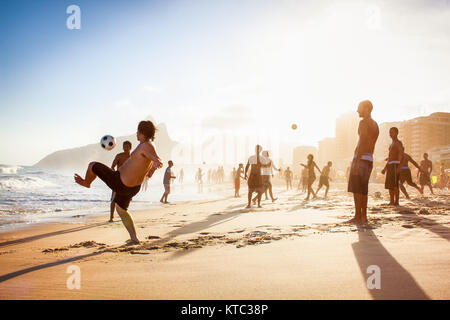 RIO DE JANEIRO, Brasile - 24 Aprile 2015: Carioca brasiliani giocando altinho futebol calcio sulla spiaggia dando dei calci a palloni da calcio al tramonto la spiaggia di Ipanema il Apr Foto Stock