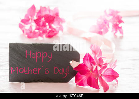 Lastra di ardesia con testo in inglese felice festa della mamma. Fiore di primavera sbocciano i fiori di ortensie. Bianco lucido Sfondo di legno Foto Stock