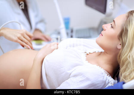 Donna incinta facendo la scansione ad ultrasuoni nella clinica prenatale, madre preoccupata per la salute del suo futuro bambino, felice momento della gravidanza Foto Stock