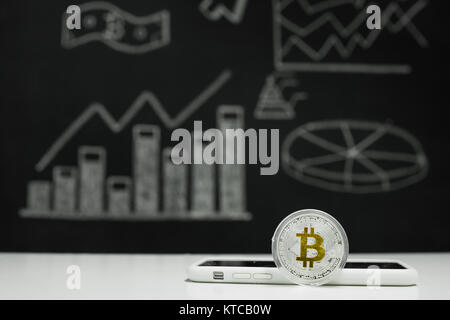 Argento bitcoin accanto allo smartphone. Crypto valuta. Denaro virtuale. BTC. Foto Stock