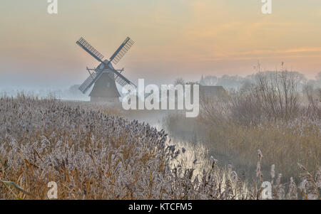 Il mulino a vento di legno nel vago paesaggio olandese di sunrise con rime Foto Stock