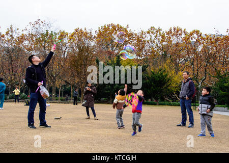 Famiglia con bambini in piedi su erba aperta patch nel parco giochi e giocare con acqua bolle d'aria Foto Stock
