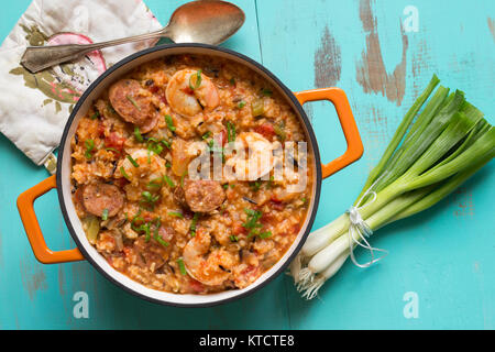 Una ghisa vaso riempito con Jambalaya su una tabella di turchese. Foto Stock