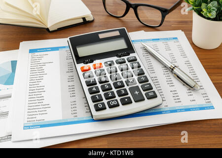 La contabilità finanziaria con la calcolatrice e i dati di contabilità sulla tavola di legno Foto Stock