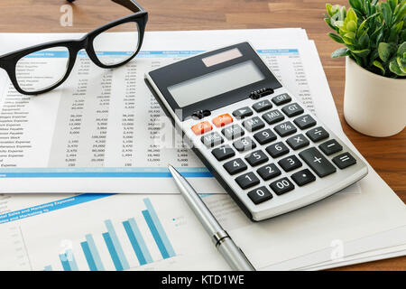 La contabilità finanziaria con la calcolatrice e i dati di contabilità sulla tavola di legno Foto Stock