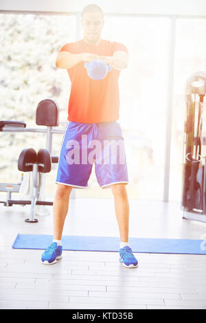 Crossfit training. Uomo Fitness facendo un peso della formazione mediante il sollevamento di kettlebell. Giovane atleta facendo kettlebell altalene. Bodybuilder kettlebell di sollevamento. C Foto Stock