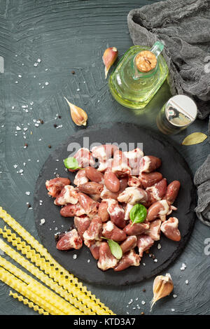 Il pollo crudo carne (fegato cuore), pasta di pomodoro, aglio e spezie al buio su un sfondo di ardesia. Appartamento laico, vista dall'alto. Foto Stock