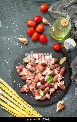 Il pollo crudo carne (fegato cuore), pasta di pomodoro, aglio e spezie al buio su un sfondo di ardesia. Appartamento laico, vista dall'alto. Foto Stock