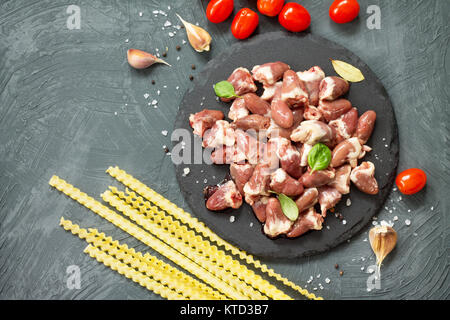 Il pollo crudo carne (fegato cuore), pasta di pomodoro, aglio e spezie al buio su un sfondo di ardesia. Appartamento laico, vista dall'alto con copia spazio. Foto Stock