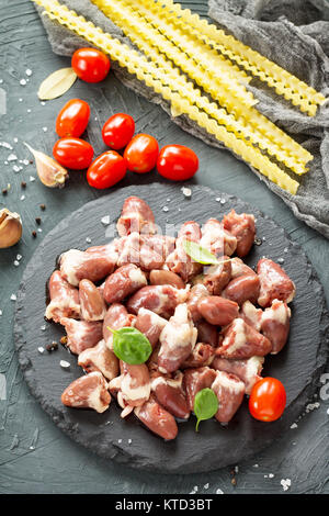 Il pollo crudo carne (fegato cuore), pasta di pomodoro, aglio e spezie al buio su un sfondo di ardesia. Foto Stock