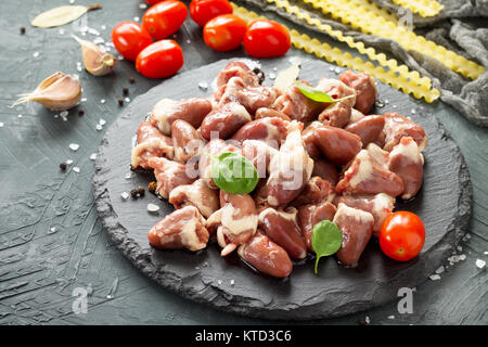 Il pollo crudo carne (fegato cuore), pasta di pomodoro, aglio e spezie al buio su un sfondo di ardesia. Foto Stock