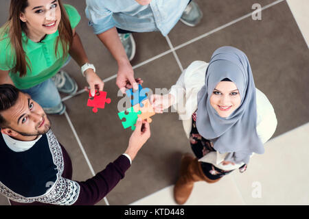 Lavoro di squadra di partner. Concetto di integrazione e di avvio con i pezzi del puzzle, gli studenti, i colleghi di lavoro Foto Stock