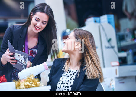 Cura dei capelli -. Bella lunga donna dai capelli Capelli di asciugatura nel negozio di elettronica Foto Stock