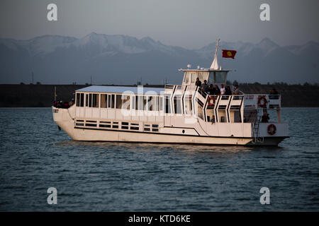 Un privato yacht crociere al tramonto sul Kirghizistan Issyk-Kul lago vicino la città di Karakol. Foto Stock