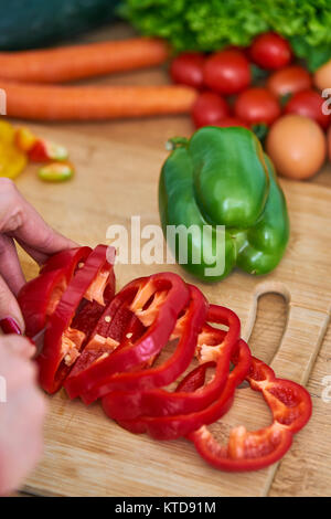 Primo piano di una giovane donna di taglio di un po' di frutta e verdura per fare di se stessa un succo sano a casa Foto Stock