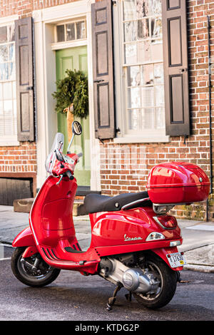 Un rosso scooter Vespa parcheggiata di fronte una storica casa decorata con una ghirlanda di Natale su Tradd Street a Charleston, Sc. Foto Stock