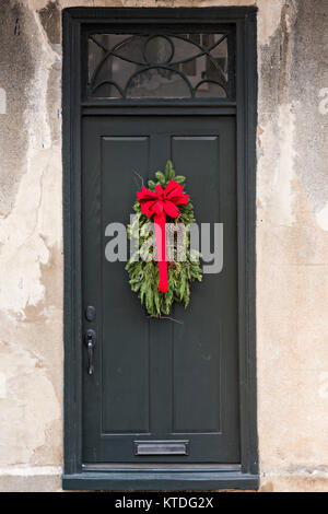 Un nero porta di legno su una storica casa decorata con una ghirlanda di Natale su Tradd Street a Charleston, Sc. Foto Stock