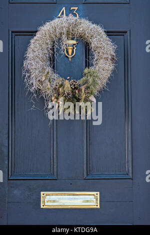 Un basso in stile country ghirlanda di Natale fatto da muschio Spagnolo pende da una porta di legno su una storica casa lungo la batteria in Charleston, Sc. Foto Stock