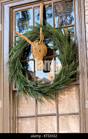 Una ghirlanda di Natale pende da una finestra su una casa storica lungo Church Street a Charleston, Sc. Foto Stock