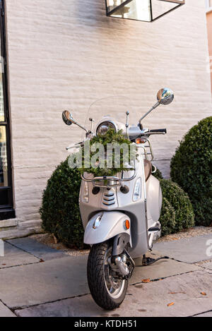 Una ghirlanda di Natale pende da una scooter Vespa parcheggiata di fronte una casa storica lungo Church Street a Charleston, Sc. Foto Stock