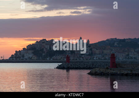 Drammatiche le nuvole colorate al tramonto con il cityscape silhouette. Imperia, Italia Foto Stock