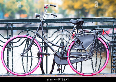 Pink bike sul ponte in Amsterdam, Paesi Bassi. Bellissima vista sui canali in autunno Foto Stock