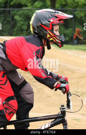 Ragazza pilota in tuta rossa. Piloti a Kettering BMX gara in notturna. BMX via, Delco Park, Kettering, Dayton, Ohio, Stati Uniti d'America. Foto Stock