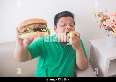 Il sovrappeso uomo scegliendo sani e freschi Apple invece di junk food Foto Stock