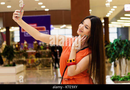 La ragazza scatta foto di se stessa su incorporato nella fotocamera del suo telefono cellulare. Foto Stock