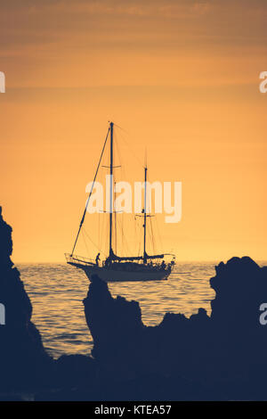 Silhouette di una barca a vela al tramonto in barca a vela da Newport Beach in California con Isola di Santa Catalina in background Foto Stock