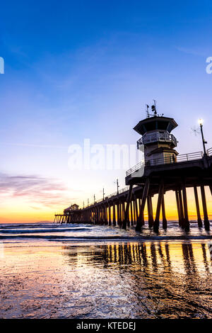 Paesaggio surreale come il sole tramonta sotto l'orizzonte lungo Huntington Beach, colata di un bagliore bellissimo e tranquillo paesaggio. Foto Stock