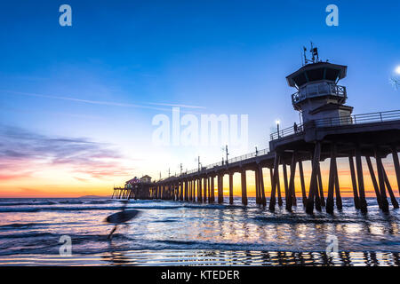 Paesaggio surreale come il sole tramonta sotto l'orizzonte lungo Huntington Beach, colata di un bagliore bellissimo e tranquillo paesaggio. Foto Stock