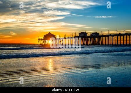 Paesaggio surreale come il sole tramonta sotto l'orizzonte lungo Huntington Beach, colata di un bagliore bellissimo e tranquillo paesaggio. Foto Stock