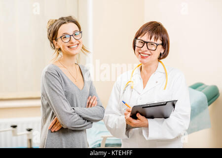 Ritratto di un sorridente giovane donna paziente e senior ginecologo durante la consultazione in ufficio Foto Stock