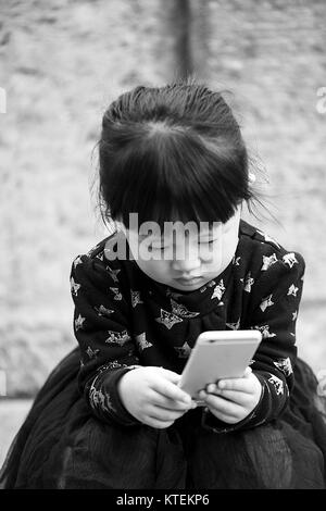 Xian,Cina - Ottobre 22,2017: bambina gioca con l'iphone sulla strada a ottobre 22, in Cina. Foto Stock