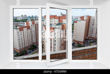 Vista attraverso la finestra in pvc frame sul balcone sul piano alto a multi-edifici di appartamenti Foto Stock