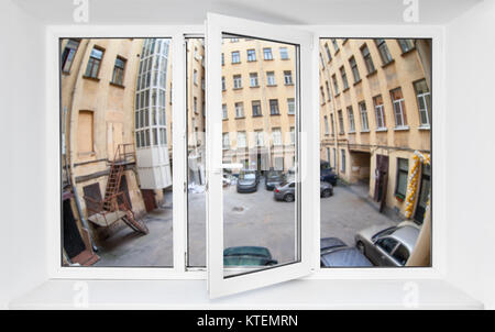 Vista attraverso la finestra in pvc telaio sul primo piano in corrispondenza della stretta del quadrangolo di automobili parcheggiate Foto Stock