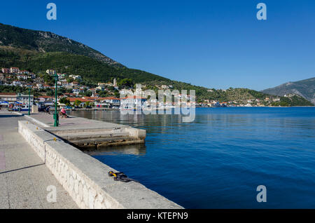 Vista in primo piano il molo quindi il porto con le sue barche da pesca ormeggiate le strutture portuali e infine le montagne che circondano il porto di va Foto Stock