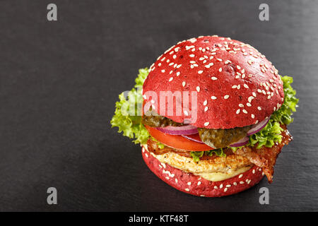 Colorate di rosso gli hamburger. In casa americana hamburger di pollo hamburger withbeetroot panini e verdure. Cibo alla moda. sfondo di ardesia. Foto Stock