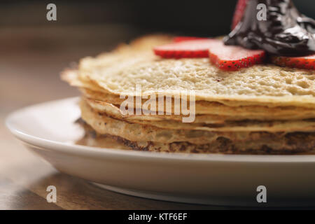 Premio cioccolato fondente versato su blinis con fragola Foto Stock