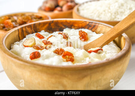 Latte di riso porridge con noci e uvetta in ciotole di legno su un bianco tavolo in legno Foto Stock