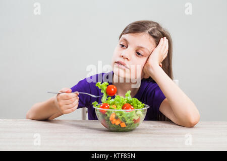 Bambina è infelice perché non le piace mangiare insalata. Foto Stock