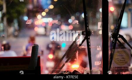 Sparare attraverso il vetro guardando fuori dall'interno dell'autobus bokeh colpo di traffico notte offuscato luci auto a Bangkok Thailandia Foto Stock