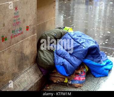 Glasgow, Scotland, Regno Unito 24 Dicembre.UK Meteo: pioggia e vento salutare i last minute la vigilia di Natale gli amanti dello shopping a Buchanan Street, Glasgow stile del miglio con persone senza dimora sulla strada. Credito traghetto Gerard/Alamy news Foto Stock